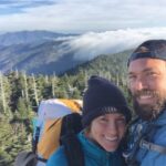 Young couple facing the camera with a mountainous landscape behind them