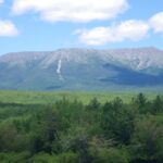 View of mountain in distance and green hills in foreground