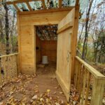 Door opened to a wooden privy in the forest