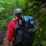 Hiker with bear canister while hiking through the Green Tunnel. Photo courtesy of BearVault