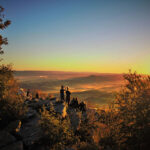 Hikers admire the sunset overlooking a valley