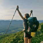 Hiker holds up trekking poles in celebration