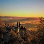 Hikers watch the sunset over a valley