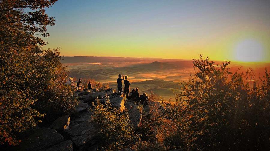 Hikers watch the sunset over a valley