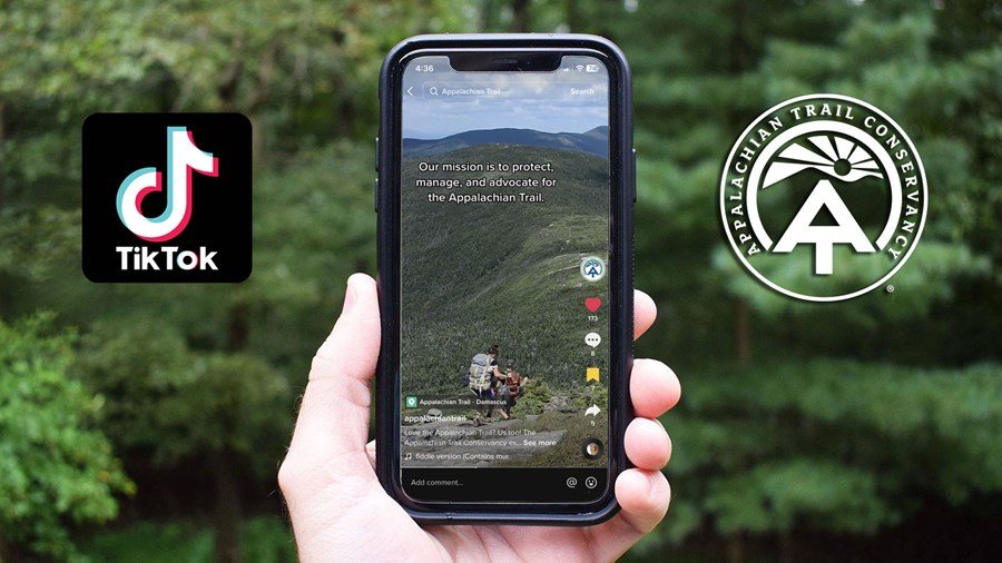 Photo of an iPhone in someone's hand. On the phone screen, the ATC's first TikTok plays between the TikTok logo and ATC logo.