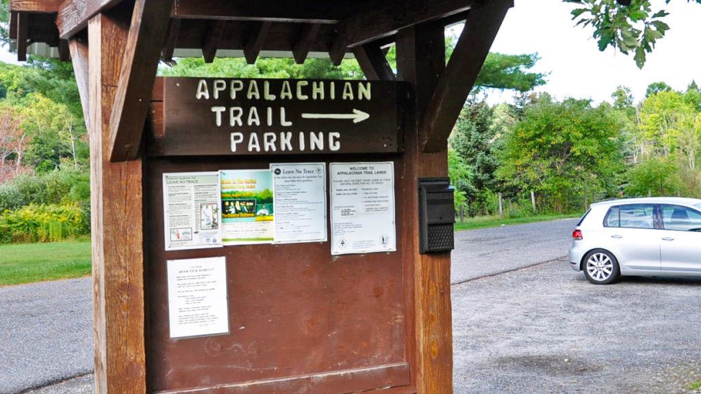 Wooden kiosk with sign pointing to an Appalachian Trail parking lot