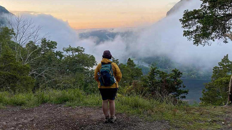 Hiker takes in the view of mist-shrouded mountains