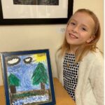Student poses for a photo next to original artwork