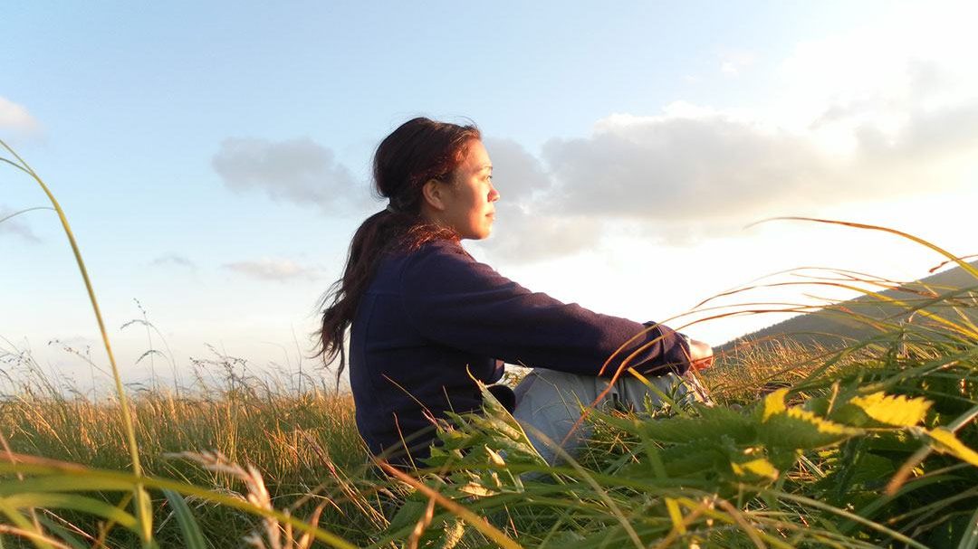 A woman sits on a grassy hill in North Carolina