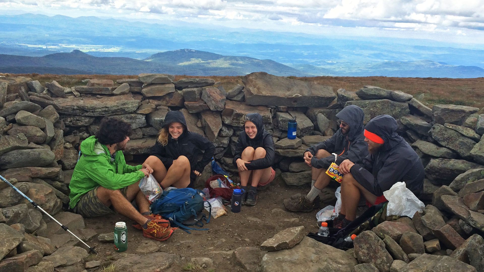 Group of hikers enjoy snacks on a mountain summit
