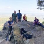 Group of hikers on rocky overlook with vista behind them