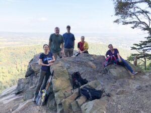 Group of hikers on rocky overlook with vista behind them