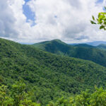 Green mountains with blue sky and white fluffy clouds