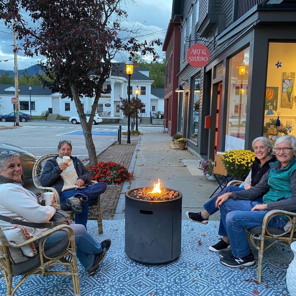 People sitting around a firepit outside a shop