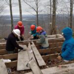 Five people work to dismantle the floor of the old shelter