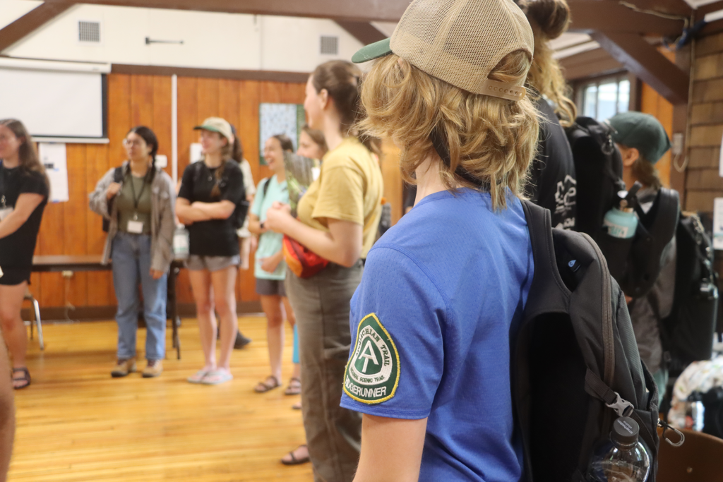 Ridgerunner wearing a patch on her sleeve stands in a circle with other trainees during the start of the Ridgerunner season.