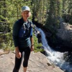 Volunteer Malin Clyde stands in front of a waterfall.