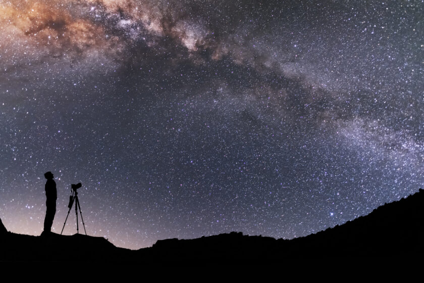 the-man-silhouette-with-camera-and-tripod-stands-on-the-hill-and-looking-at-the-bright-milky-way-galaxy-beautiful-night-landscape