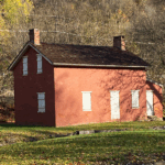 Red brick lockhouse building with white wooden door next to canalway