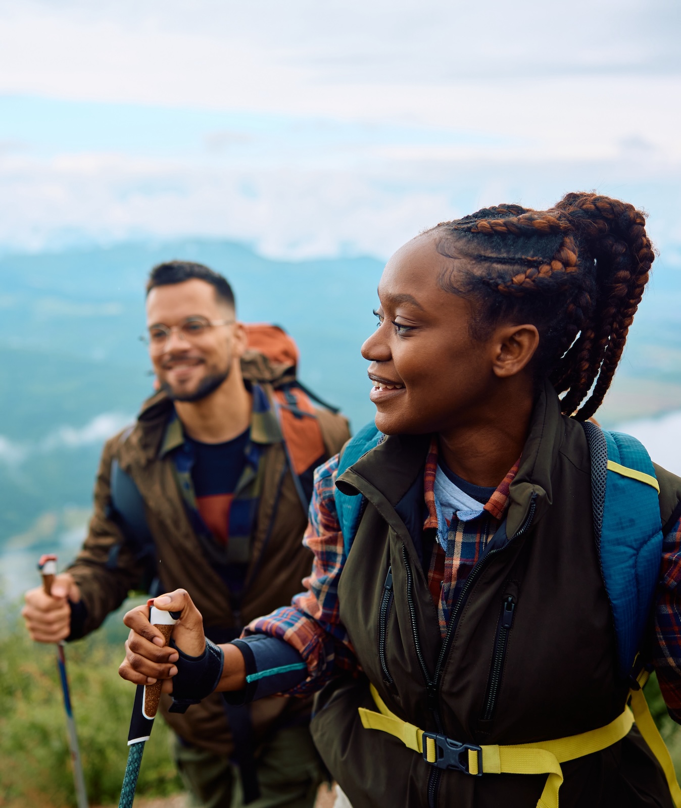 Couple of hikers walking on a hill while using hiking poles. 