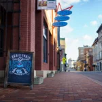 Chalkboard sign promoting Broad Porch Coffee Company next to a brick building downtown