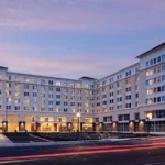 Modern large hotel building with lights on at dusk.