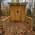Wooden privy with accessible ramp entrance