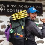 Hiker poses with packed backpack in front of Appalachian Trail Conservancy headquarters