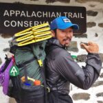 Hiker poses with packed backpack in front of Appalachian Trail Conservancy headquarters