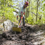 Volunteer uses handtools to clear the Trail's treadway