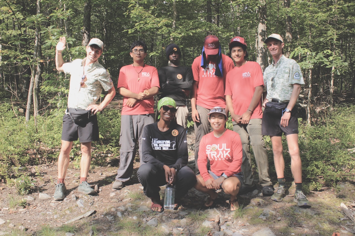 Group of Soul Trak hikers in Soul Trak T-shirts posing with two Appalachian Trail Ridgerunners.