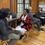 Angelique Redwood (center) smiles while conversing with a partner during an indoor learning activity.