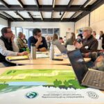 Small group discusses over a table with laptops, notebooks, and ATCCC materials.