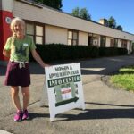 Volunteer poses next to a-frame sign reading "Monson & Appalachian Trail Info Center"