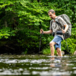 Hiker wading through a river, water at mid-calf level.