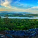 A circular band of fog surrounds a green farmland landscape viewed from the Appalachian Trail.