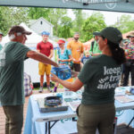 A volunteer selects a raffle ticket from inside a bear canister during Trail Days 2025.