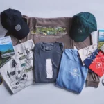 Assorted Appalachian Trail merchandise laid out on a brown backdrop: t-shirts, caps, maps, guidebooks, patches, and souvenirs.
