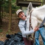 Anne Sentz smiling while adjusting a pack mule’s bridle.