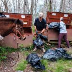 Volunteers and staff unload mulch into large metal containers.