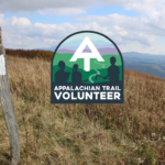 Photo of a white blaze on a wooden post in front of a field on the Appalachian Trail